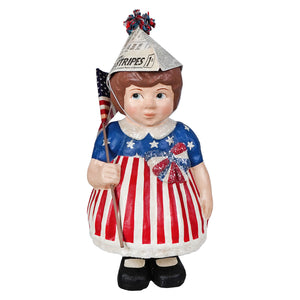 A painted resin betsy ross display figure of a girl in a red white and blue striped dress with glittery stars and a newspaper hat