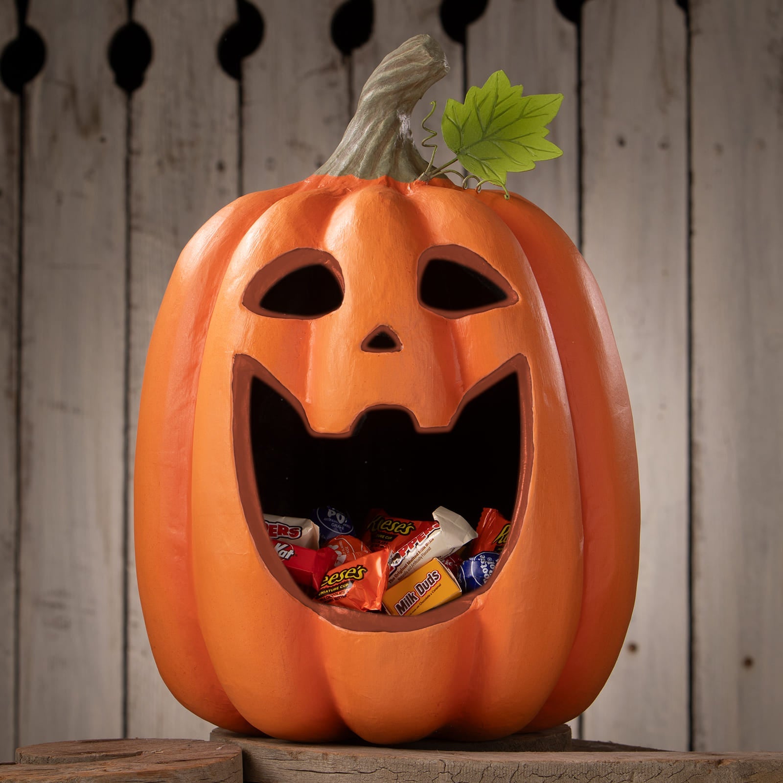 Orange plastic big mouth jack o lantern candy bucket with carved face green leaf and stem halloween pumpkins and gourds