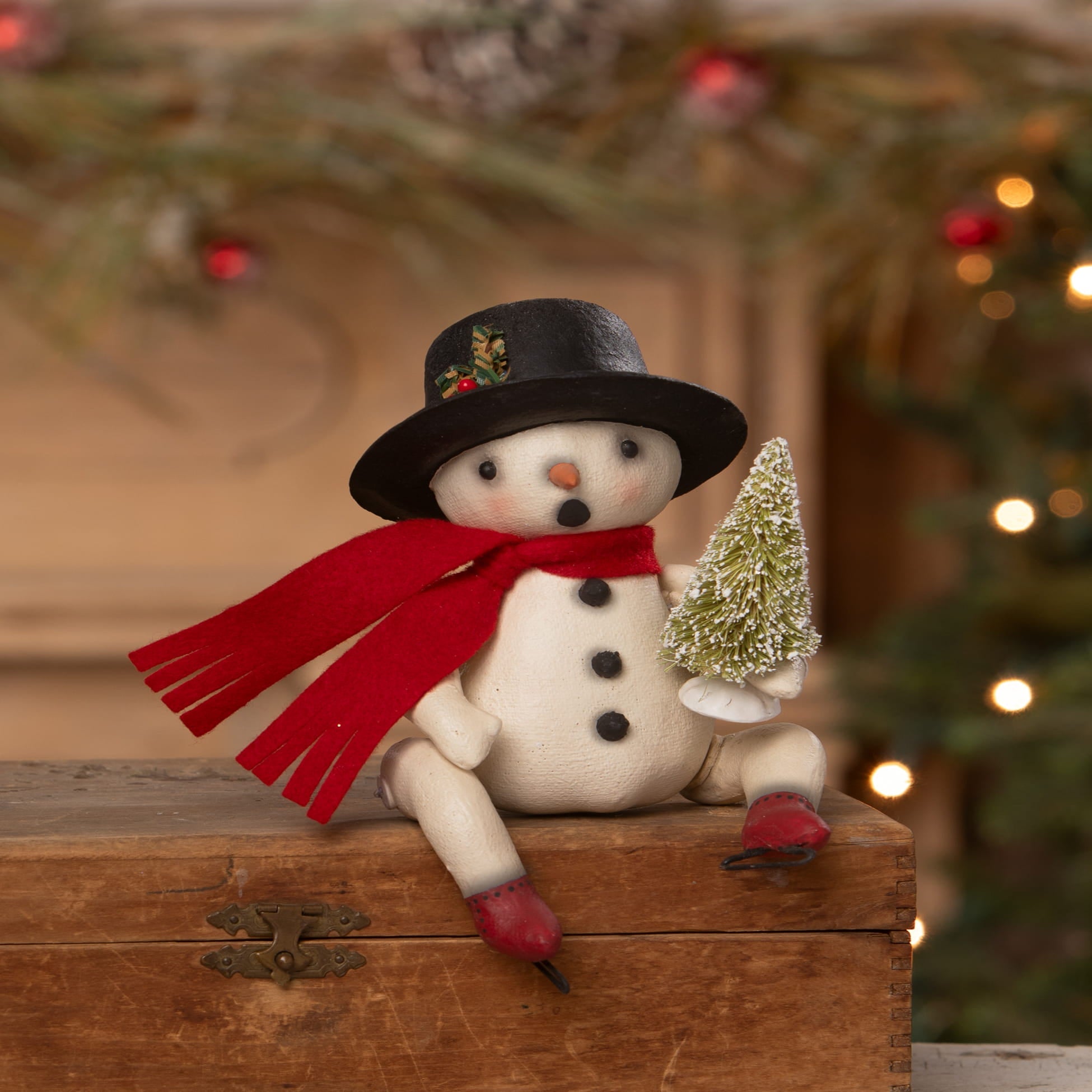 A charming white snowman figurine by bethany lowe designs wearing a black top hat and red scarf holding a frosted tree bing