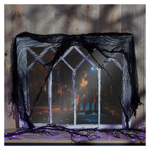White distressed window frame decorated with black gauze cloth spiderweb and purple string lights for halloween decor