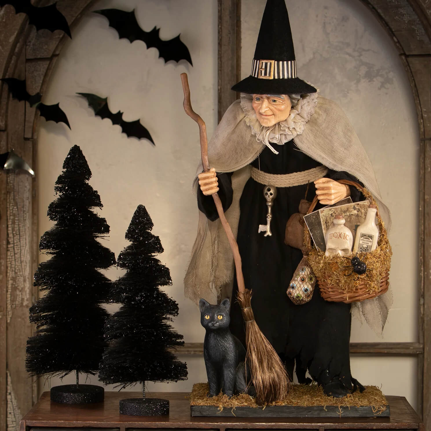 Detailed witch figurine in black striped hat holding broomstick with basket for black stripes delights bottle brush trees set