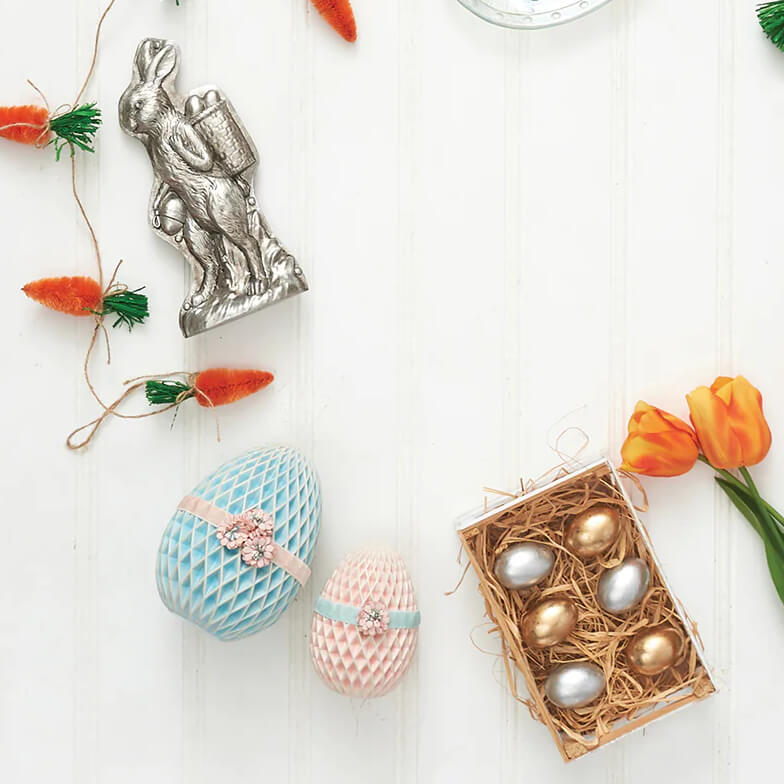 Decorative Easter display featuring honeycomb paper eggs, metallic ornaments, tulips, and a nest with silver and gold eggs.