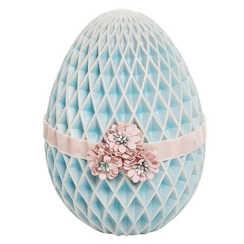 Decorative light blue egg with diamond quilting pattern and pink floral ribbon accent.