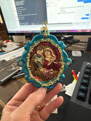 Blue nativity ornament is a teal and gold ornamental christmas tree decoration featuring a painted holy family scene