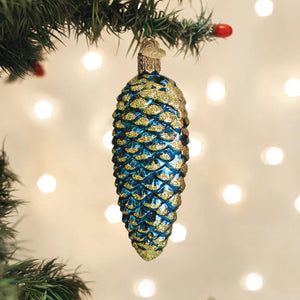 Blue shimmering cone ornament with blue and gold glitter pinecone hanging from a christmas tree branch