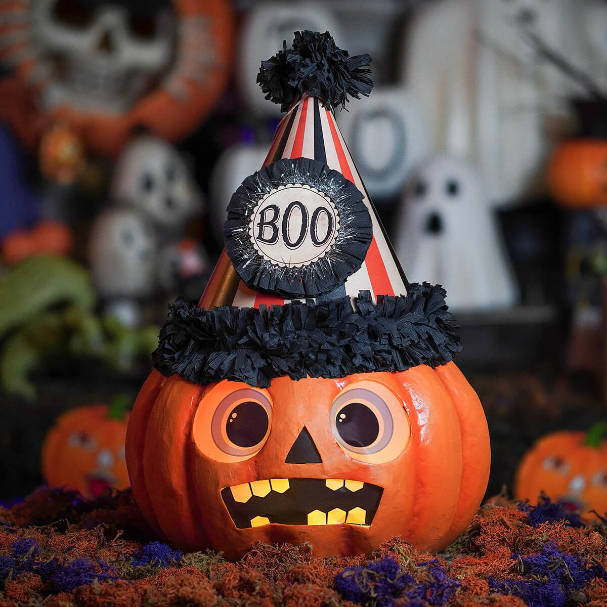 A festive orange boo party pumpkin lantern with a striped party hat black tassels and a boo badge for halloween pumpkins