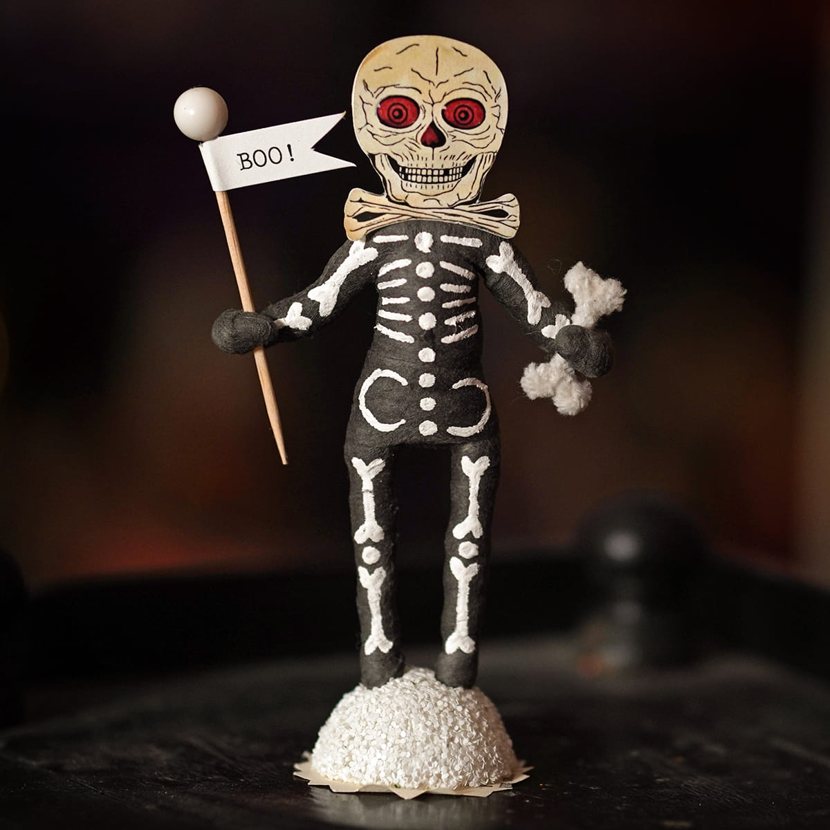 Boo skeleton figure with beige skull red eyes white bones on black body holding boo flag for halloween decor
