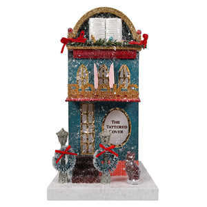 Teal and gold glittery cody foster book shop figurine with snow dusted facade red ribbon and decorative windows light cord