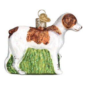 A brittany spaniel ornament featuring a white and brown spotted glass dog with glittery green grass at its feet