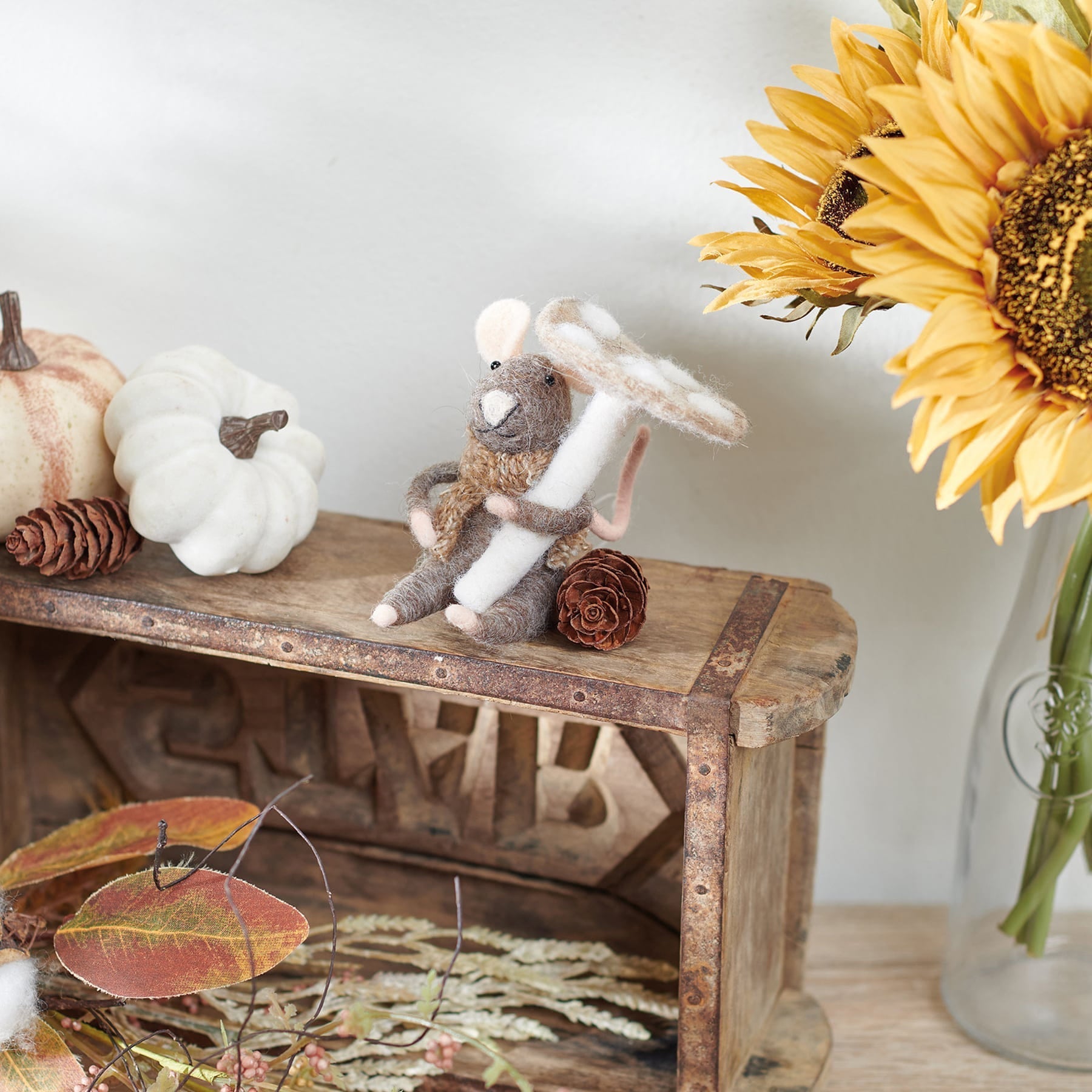 A charming brown mushroom mouse critter needle-felted with gray and beige wool holding a white witch switch object
