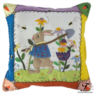 A charming felt easter bunny garden pillow with blue plaid vest and embroidered flowers and bees on patchwork background