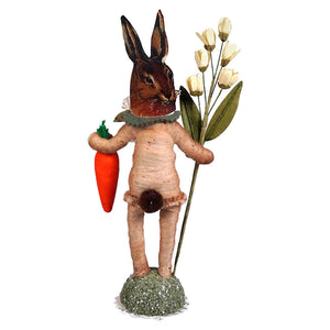 A whimsical brown bunny face garden folk art hare figure with a textured body holding carrot and white flowers
