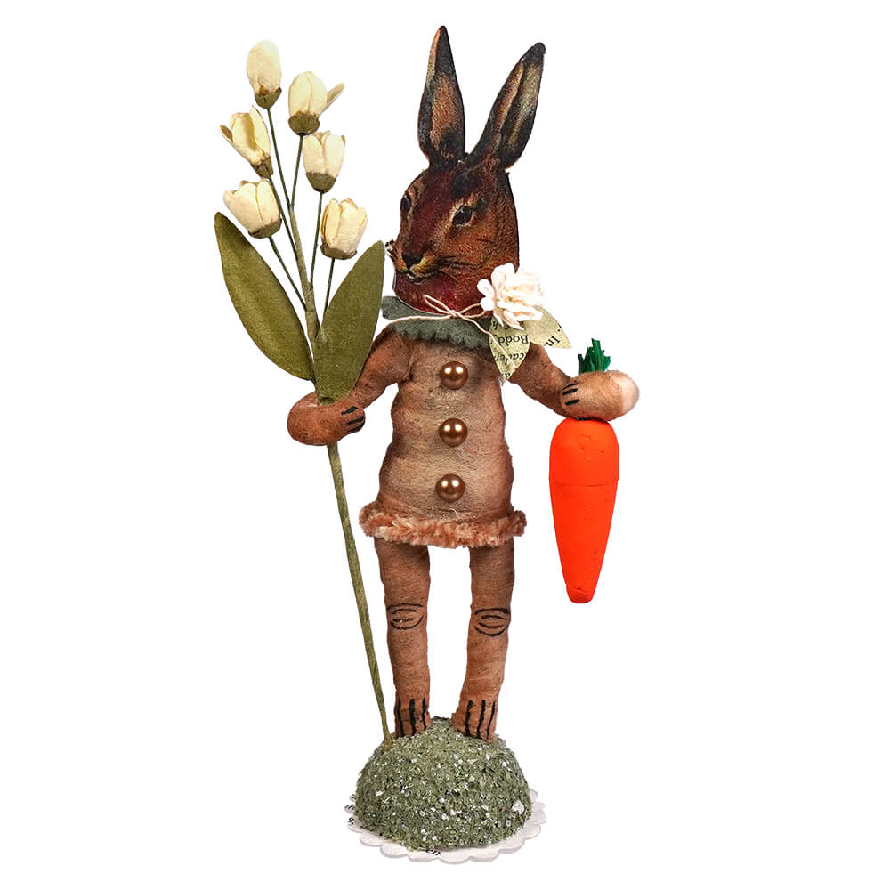 Brown bunny face garden hare figure in a buttoned coat holding white tulips and an orange carrot folk art style