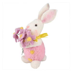 A small bunny felt ornament in pink and white holding a bouquet of purple felt flowers with a yellow ribbon