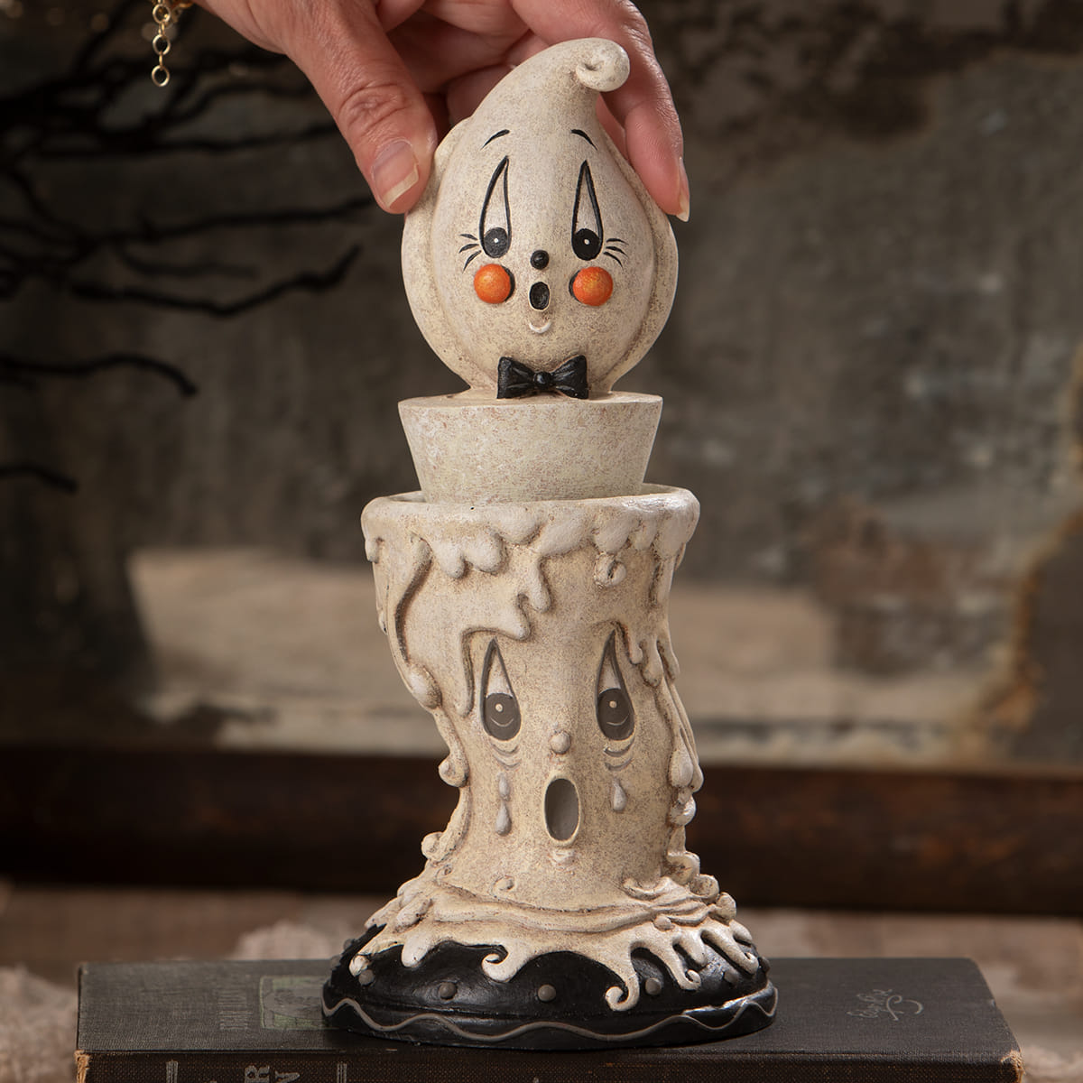 A whimsical cream ceramic candlestick ghost with orange cheeks and black bow tie perfect for johanna parker halloween decor