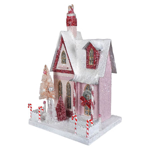 Pink glittery candy cane cottage house ornament with red accents and santa on roof spreading holiday cheer