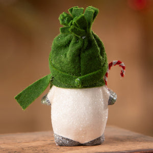 A white glittery penguin snowboy by bethany lowe designs wearing a green felt hat and scarf holding a candy cane