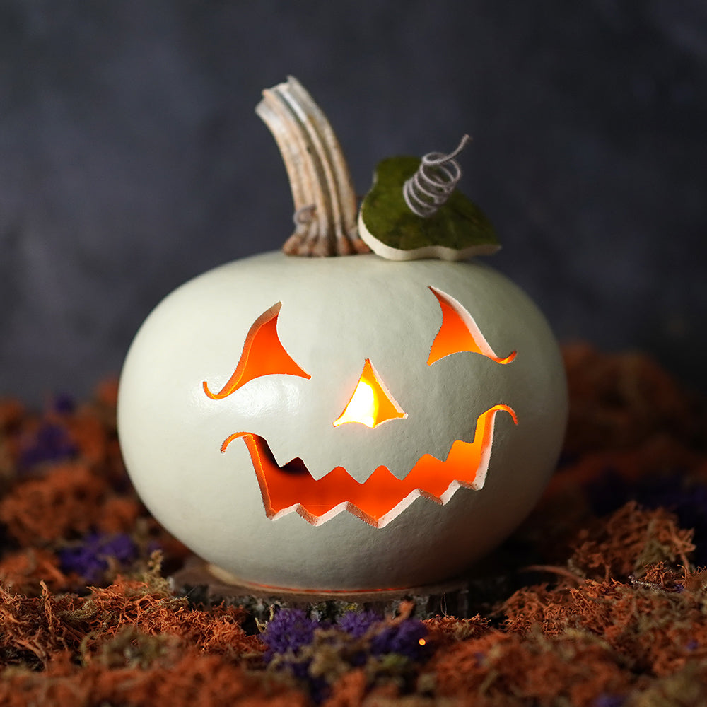 A glowing white cannon lighted jack-o-lantern gourd with orange halloween lights decor by meadowbrooke gourds artisans