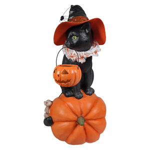 Black cat witch figurine with green eyes wearing an orange glittery hat on a pumpkin perfect for halloween witches decor