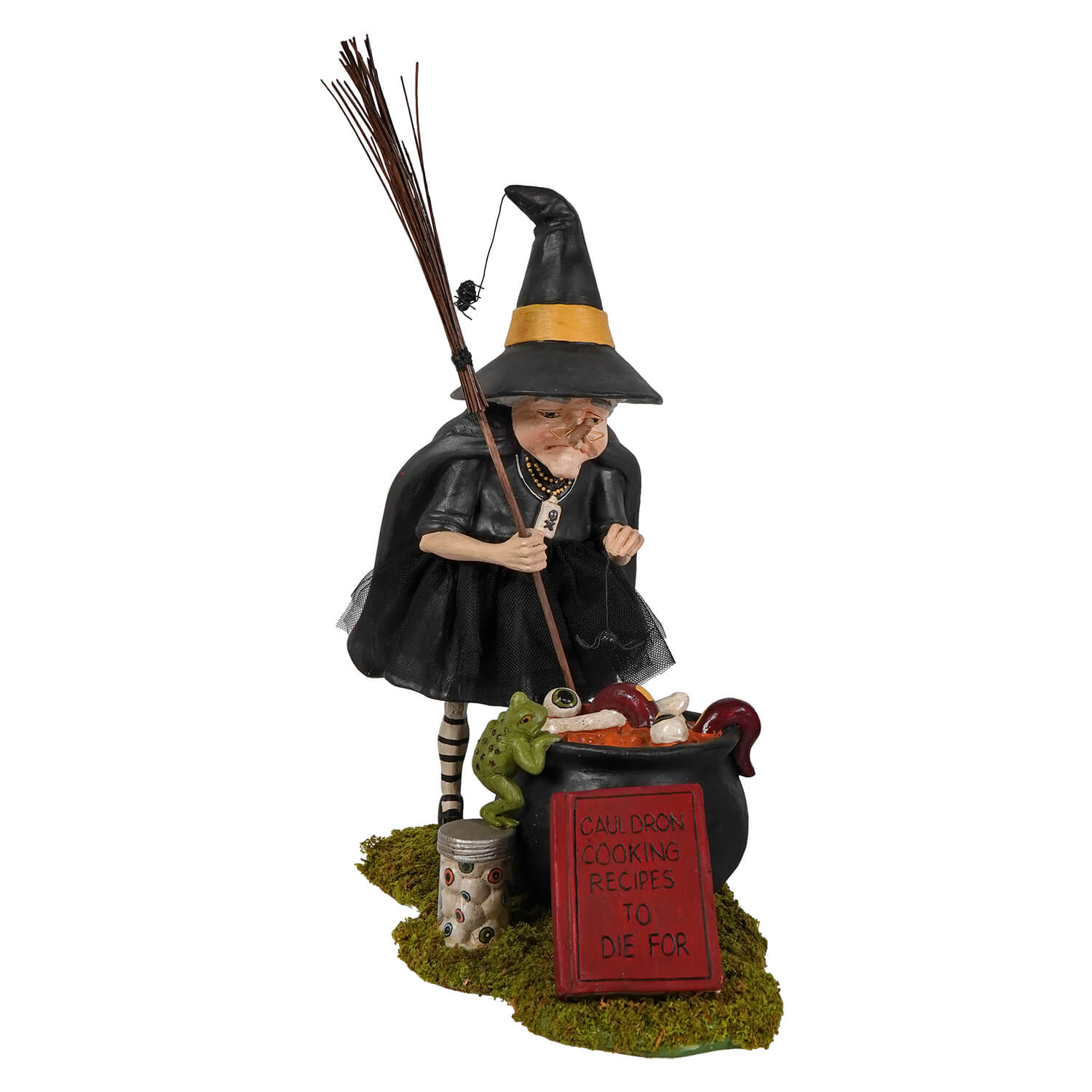 Black witch figurine with yellow-trimmed hat holding broom beside cauldron labeled children cooking recipes to die for cauldron cooking witch