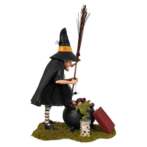 Black cauldron cooking witch figurine with yellow-trimmed hat striped stockings holding broomstick beside cauldron