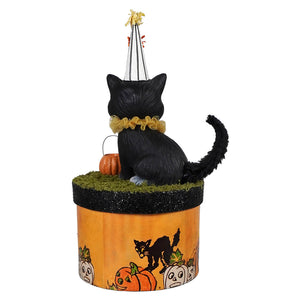 Black cecil cat figurine with striped party hat and gold collar sitting on orange glittery halloween cats pumpkin box