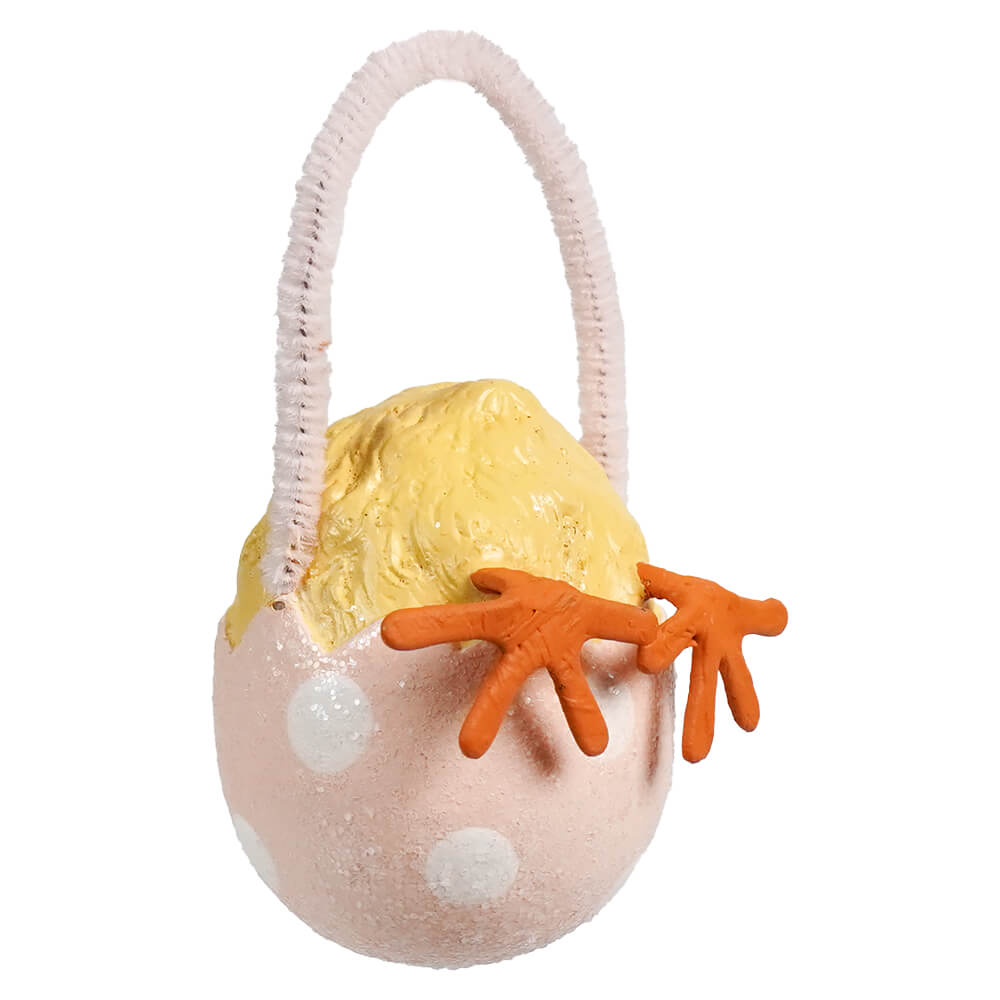 A pink polka-dotted bethany lowe chick tail ornament egg with a yellow chick and white handle for easter eggs and decorative grass