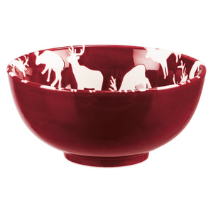 Glossy deep red ceramic christmas bowl with white deer and pine designs along the inner rim in a bowl set