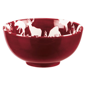 Glossy deep red ceramic christmas bowl with white deer and pine designs along the inner rim in a bowl set