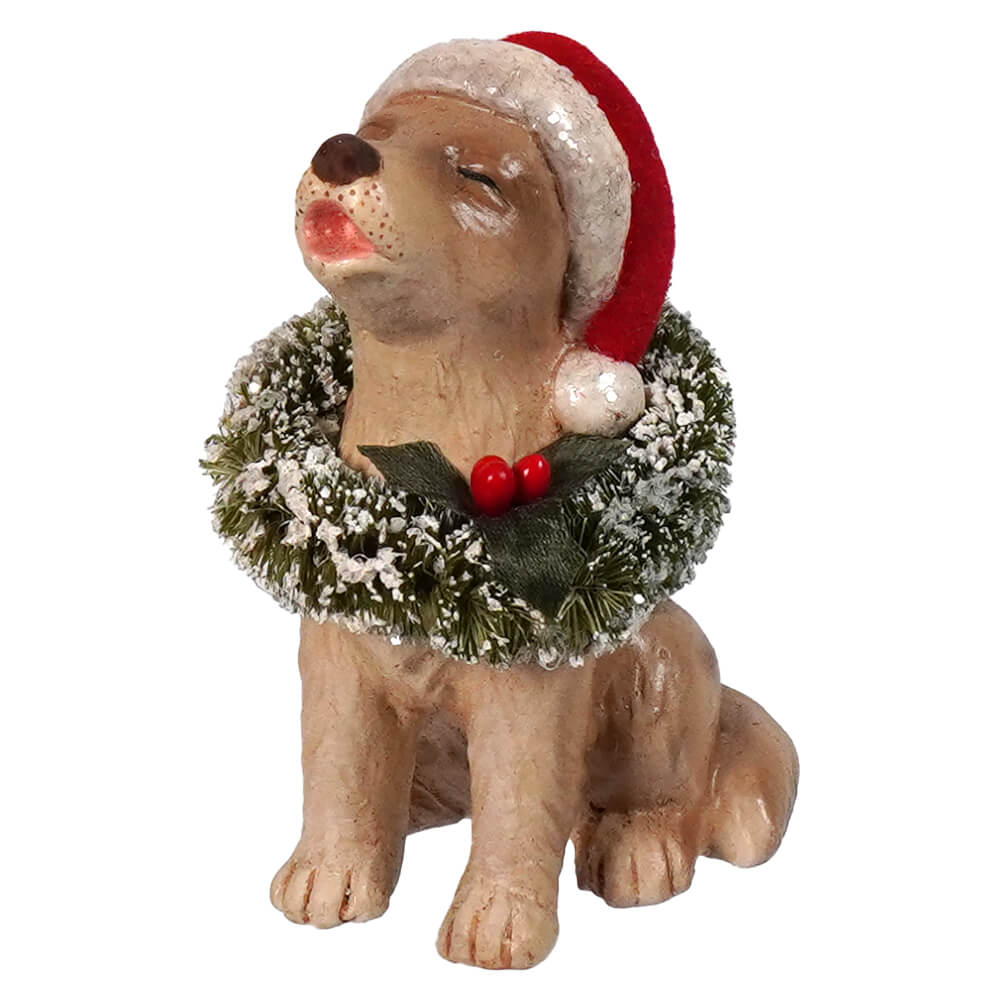 A tan resin bethany lowe design christmas caroling dog figurine wearing a red santa hat and frosted holly wreath
