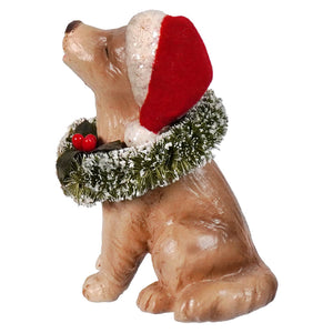 A tan resin bethany lowe design christmas caroling dog figurine wearing a santa hat with snow-dusted green garland