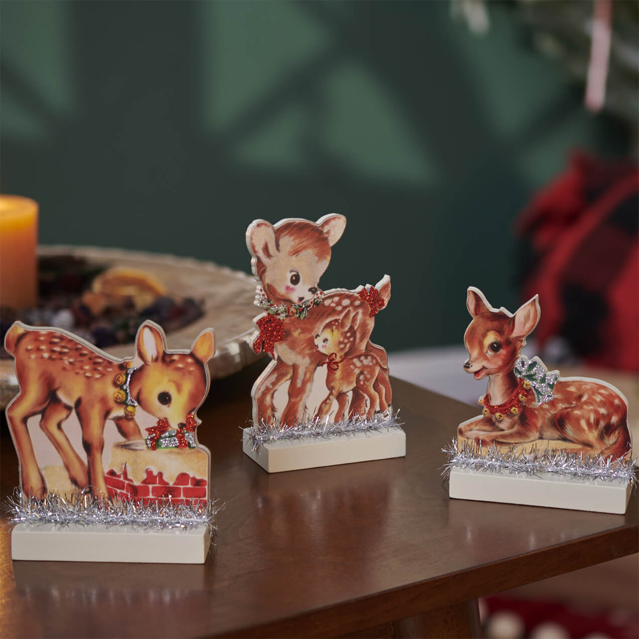 Decorative figurines of deer or fawns with festive holiday accessories on small bases.