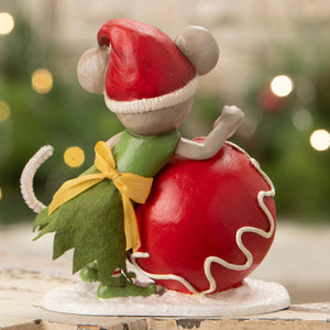A bethany lowe design christmas mouse gidget figurine in red santa hat and green dress sitting on a glossy red ornament