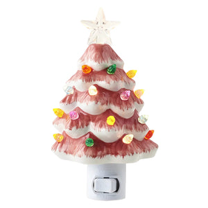 A pink and white ceramic christmas tree night light with colorful glowing bulbs and a clear star on top