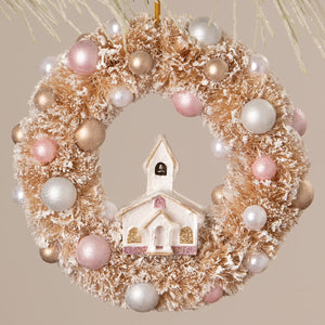 A bethany lowe frosted gold christmas wreath ornament with pink pearls and a miniature white church in the center
