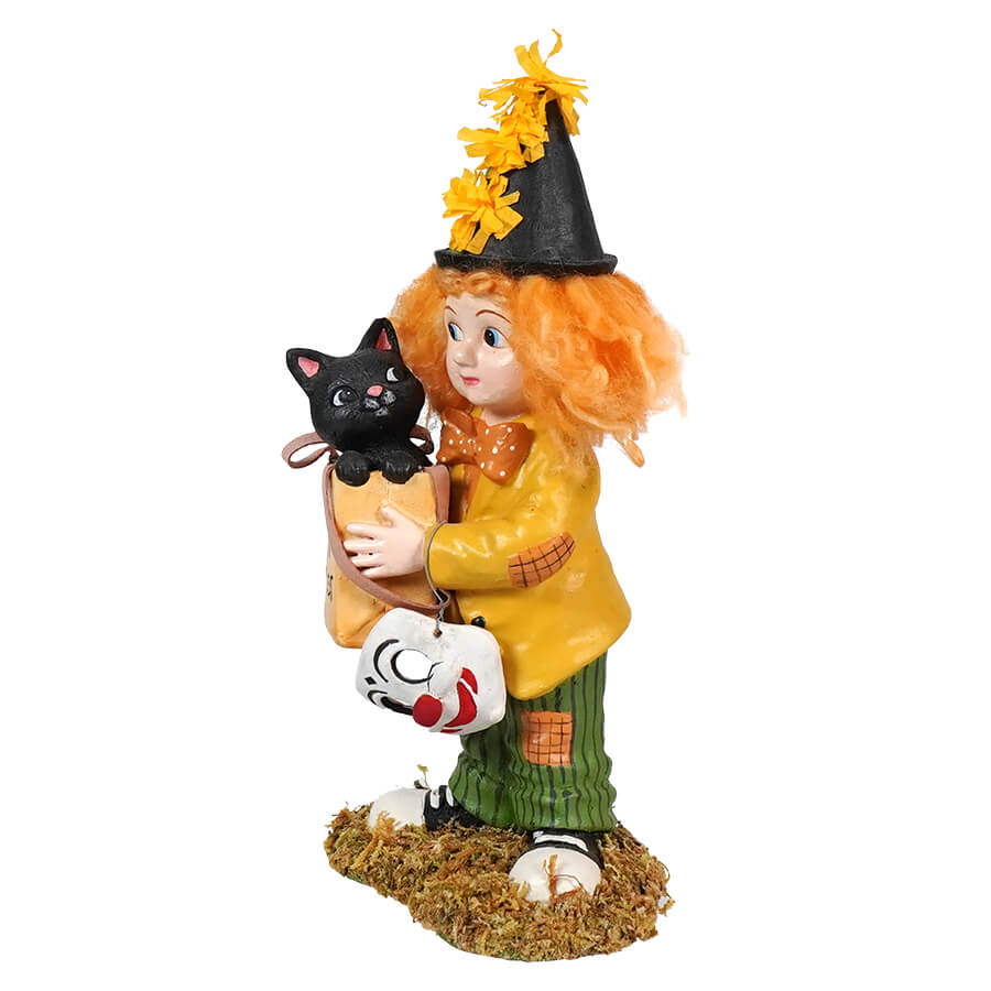 Whimsical figurine of a witch holding a black cat and a clown mask.