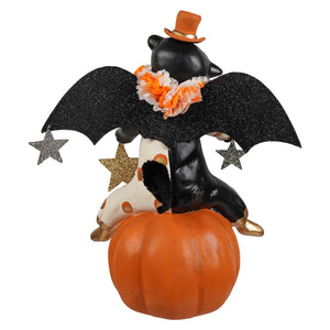 A black bat figurine with glittery wings and an orange hat on a bright jack o lantern pumpkin for bethany lowe halloween decor