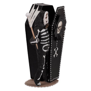 A black coffin-shaped skeleton boy decor with white bone patterns holding a sign saying im not dead
