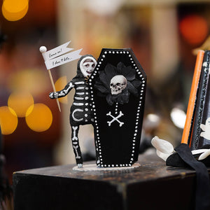 Black coffin-shaped skeleton boy decor with white dotted trim skull and crossbones and small skeleton holding a sign