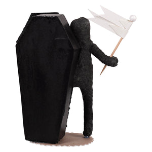 Black coffin-shaped cake topper with wire-wrapped skeleton boy figure holding white paper flag for skeleton decor