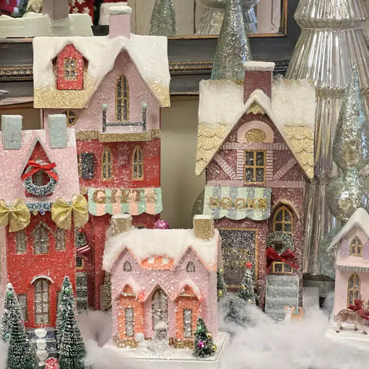 Decorative Christmas village scene with houses and trees in a snowy setting.