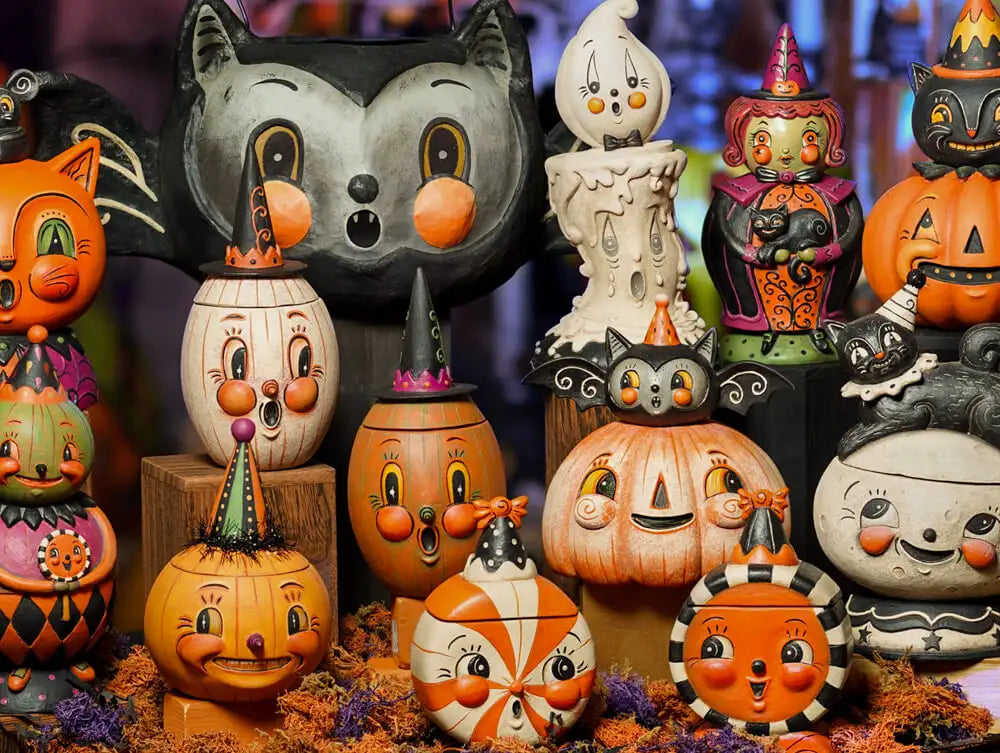 A collection of vintage-style halloween figurines, including smiling pumpkins and a black cat with bat wings.