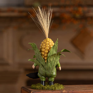 A whimsical bethany lowe corn on the cob figurine with a golden ear head and green husk outfit called corn on the cob curtis