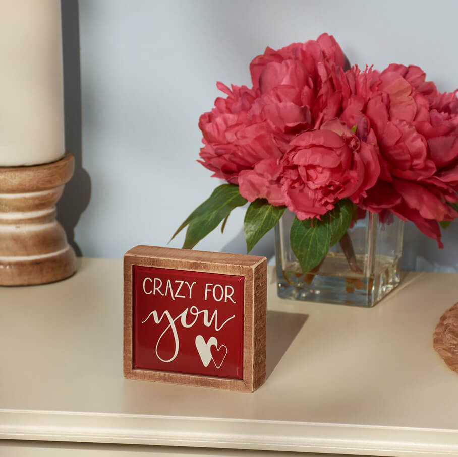 A red wooden sign with ’Crazy for you’ text and heart design.