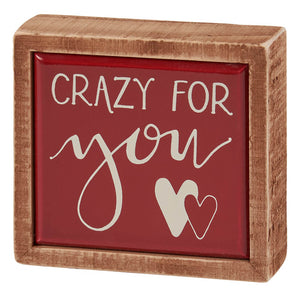 Wooden-framed decorative box sign with ’Crazy For You’ text and heart designs on a red background.
