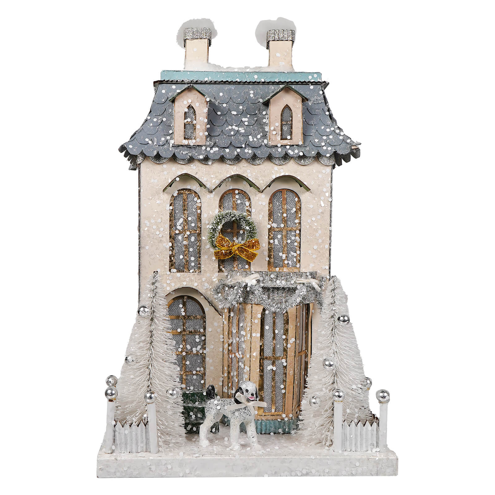 A festive white chateau house christmas village ornament with cream walls, gray roof, wreath, and frosted pine trees