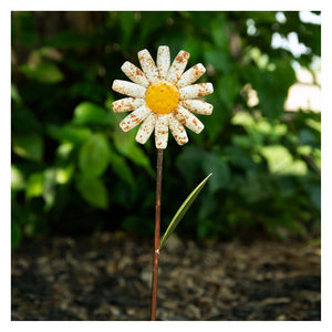 A rustic daisy garden pick with speckled white petals yellow center decor piece and copper-colored stem for garden use