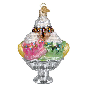 Colorful glass ice cream ornament with pink green and white scoops topped with chocolate sauce and rainbow sprinkles