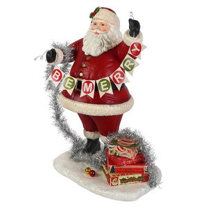 Deck the halls santa figurine by bethany lowe designs holding tinsel with be merry banner and holiday boxes, red and white folk art santa
