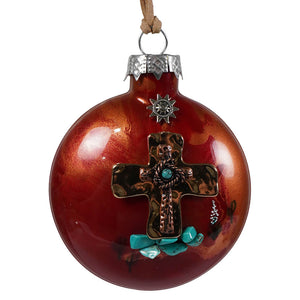Desert faith cross ornament featuring a rustic copper-tone cross with turquoise stones on a red glass background topped with a silver starburst